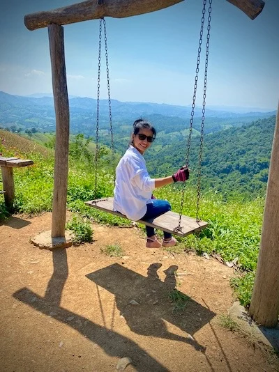 Parichad Khongon on a swing in the mountains overlooking the Thai landscape by Peter Pickering