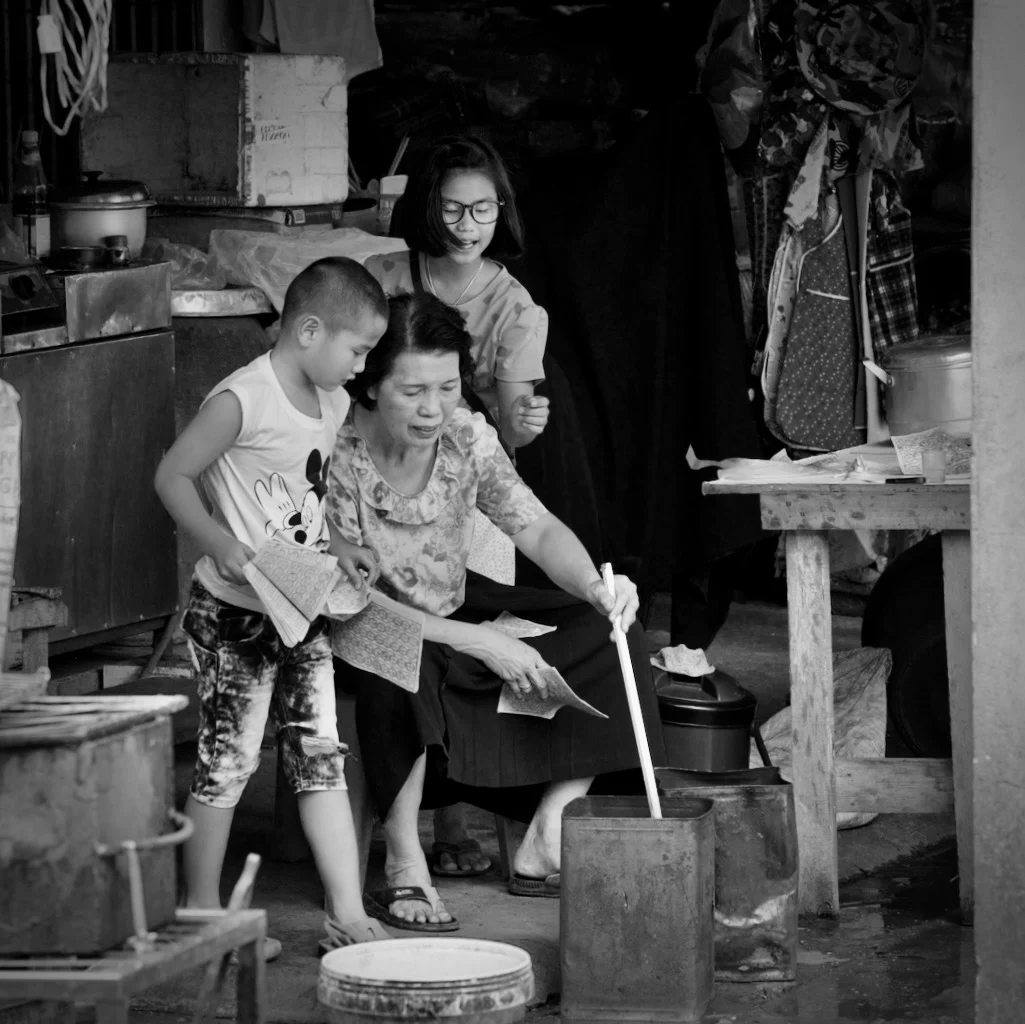 Asian family with roadside stall stirring the ashes in a tin